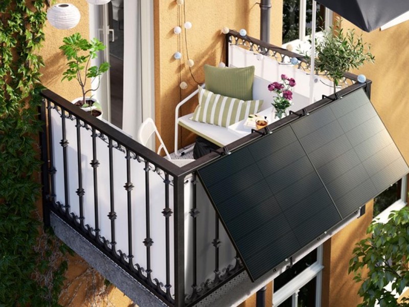 Ein wohnlich dekorierter Balkon mit Solarpanels an einem bunten Haus.