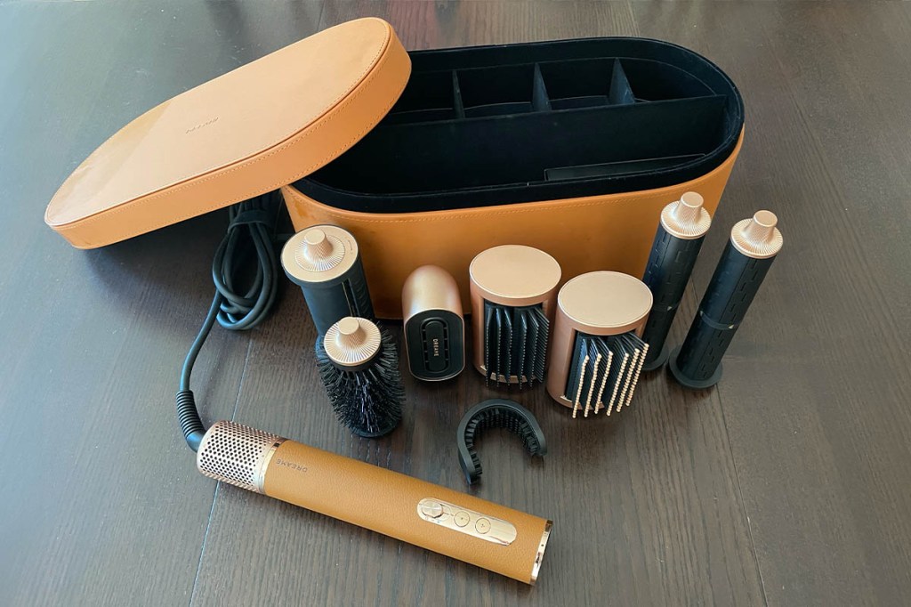 Der Dreame Airstyle Pro mit Case und allen Aufsätzen auf einem Holztisch.