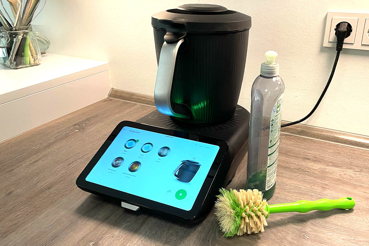 Der Thermomix TM7 in Betrieb. Daneben ein Spülmittel und eine Spülbürste.