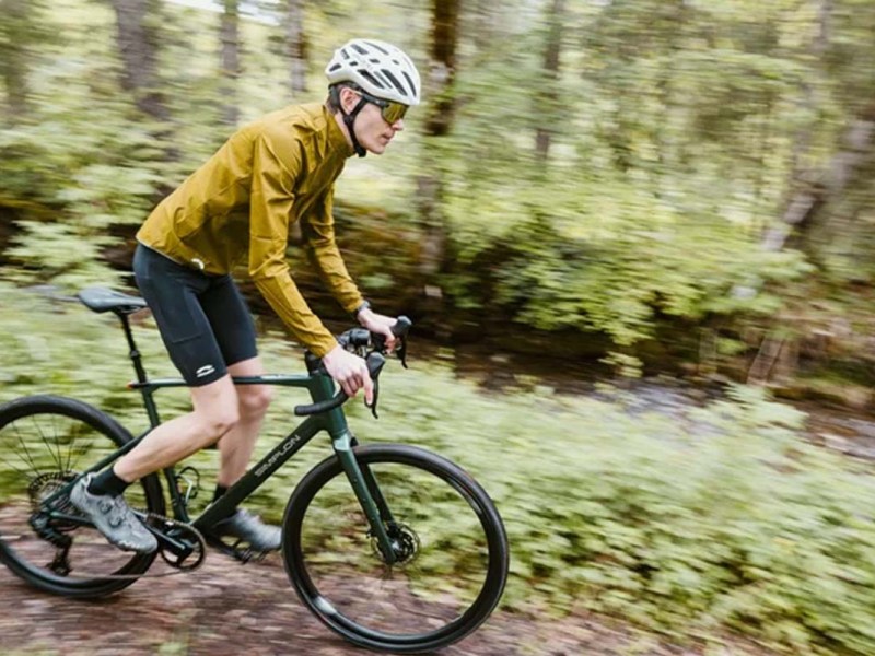 Mann fährt mit einem Gravelbike durch einen Wald