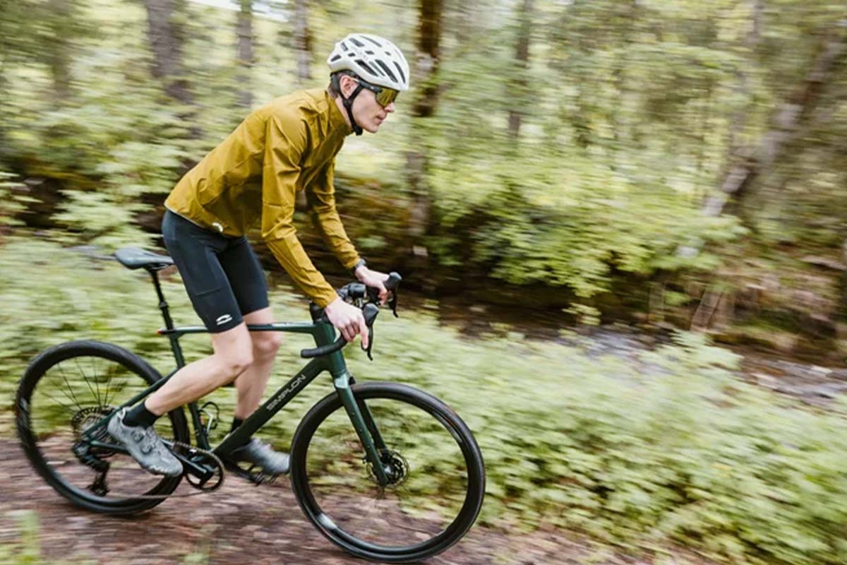 Mann fährt mit einem Gravelbike durch einen Wald