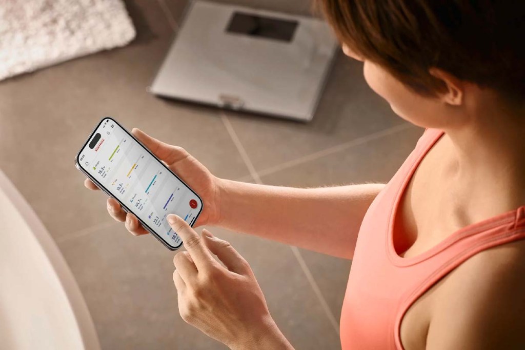 Overshoulder Blick: Frau guckt auf ihr Smartphone