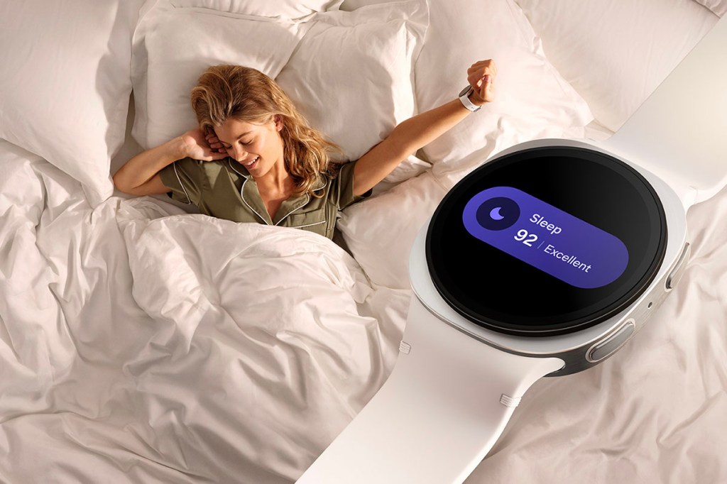 Schlafscore auf der neuen Samsung Galaxy Watch 8, dahinter eine Frau im Bett.